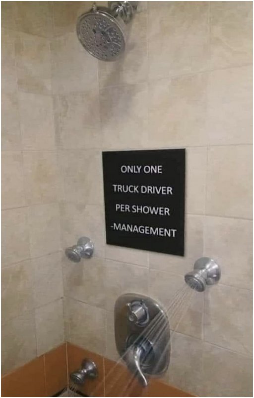 a running shower, perhaps at a truck stop, with a sign on the wall that says only one trucker per shower